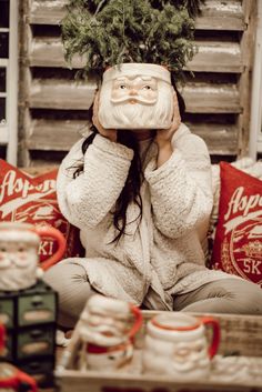 a woman sitting on top of a couch holding a christmas tree over her face and covering her eyes