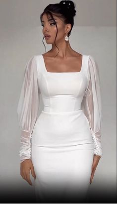 a woman wearing a white dress with sheer sleeves