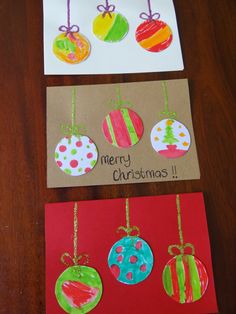 three christmas cards with ornaments hanging from them on top of a wooden table next to each other