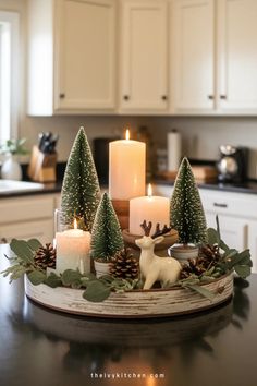 Festive holiday centerpiece with lit candles, miniature fir trees, pinecones, and a ceramic reindeer on a kitchen counter. Christmas Wine Decor, Traditional Christmas Decorations Table, Kitchen Mantle Christmas Decor, Reindeer Centerpiece Ideas, Christmas Decor Arrangements, Christmas Tree Vignettes, Christmas Farmhouse Living Room, Christmas Decor On Shelf, Simple Table Christmas Decor