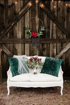 a white couch sitting in front of a wooden wall with christmas wreaths on it