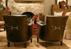 two brown leather chairs sitting in front of a fire place