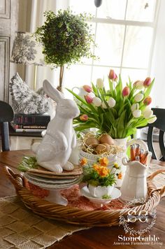 a table topped with plates and vases filled with flowers next to a bunny figurine