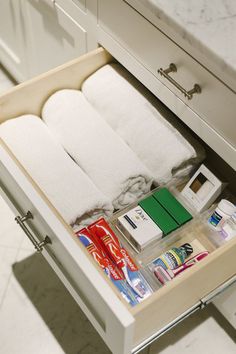 an open drawer in a bathroom filled with toiletries