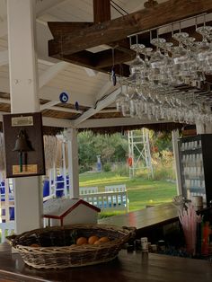 a bar with lots of wine glasses hanging from the ceiling and a basket full of oranges in front of it