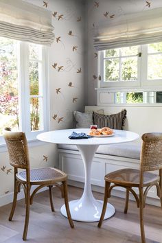 a white table with two chairs next to it in front of a window filled with windows