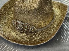 This is a gorgeous gold glitter cowboy hat adorned with a rhinestone band and gold and rhinestone center. Great for music festival or bachelorette party.  Hand decorated so no two are alike. Glitter has been sealed to help prevent shedding. Party hat. Message if you have any questions or would like to have your hat personalized. Glitter will not shed off. Elegant Gold Hat For Festival, Elegant Gold Festival Hat, Gold Fedora Hat For Rodeo, Gold Western Fedora Hat, Gold Fedora Hat For Festival, Gold Fedora Western Hat, Gold Wide Brim Hat For Party, Gold Wide-brim Hat For Party, Western Bling Hat For Rodeo