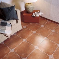 a chair and lamp in a room with tile flooring on the ground, next to a couch