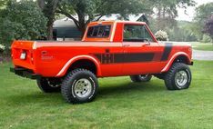 an orange truck parked on top of a lush green field