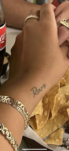 a woman with a tattoo on her arm holding onto a bottle of coke and some tortilla chips