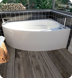 a large white bath tub sitting on top of a wooden floor next to a window