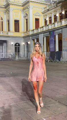 a woman in a pink dress is walking down the street