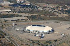 an aerial view of a large stadium in the middle of a highway and parking lot