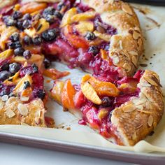 a close up of a pie on a pan with berries and almonds in it