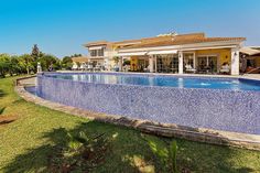 a large swimming pool in front of a house with an outdoor dining area and patio