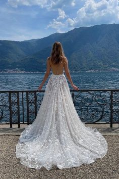 a woman in a wedding dress looking out over the water