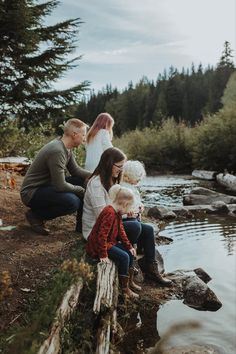 a family sitting on the edge of a river