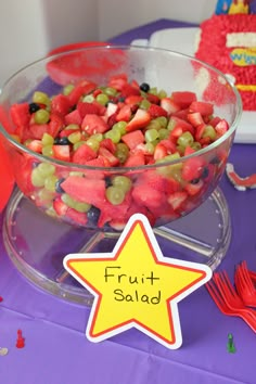 a bowl of fruit salad on a table with a star shaped sign that says fruit salad