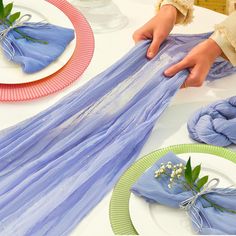 a table topped with plates and napkins covered in blue tulle