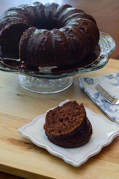 a chocolate bundt cake sitting on top of a wooden table next to a plate