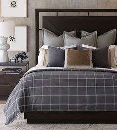 a bed with grey and white plaid comforter in a bedroom next to two nightstands