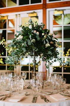 there is a vase with flowers on top of the table set for a formal dinner