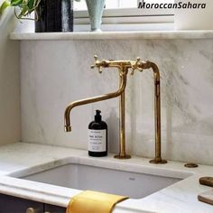 a bathroom sink with a gold faucet and soap dispenser