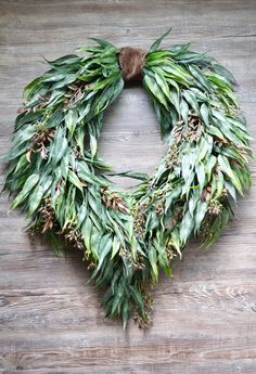 a wreath made out of green leaves on top of a wooden table