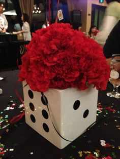 a white box filled with red flowers sitting on top of a black table covered in confetti