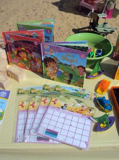 several children's books and games on a table at a beachside picnic party