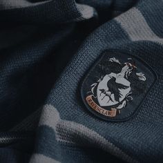 a blue and white striped shirt with a harry potter crest on the chest, close up