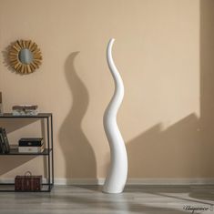 a tall white vase sitting on top of a hard wood floor next to a wall