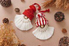 two white tasselled ornaments with red and white stripes are on a table next to pine cones