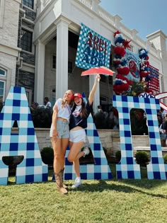 two women standing in front of a large sign with the letters usa and american flag on it