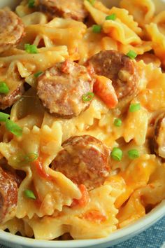 a bowl filled with pasta and meatballs on top of a blue table cloth next to a fork