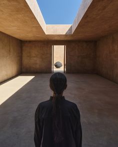 a woman standing in an empty room looking up at the sky