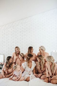 a group of women sitting on top of a bed next to each other in matching robes