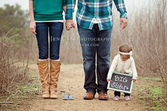 a man and woman walking down a dirt road with a small child on the ground