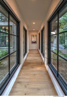 an empty hallway with large windows and wood flooring