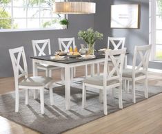 a dining room table with white chairs and a rug on the floor in front of it