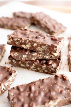 several pieces of chocolate covered granola bars on a white surface with one cut in half