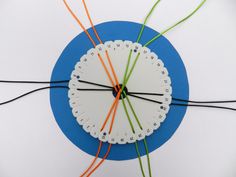 a white clock with orange and green wires connected to it on a blue circular surface