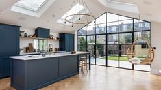 an open kitchen and dining area with skylights in the ceiling, wooden flooring and blue cabinets