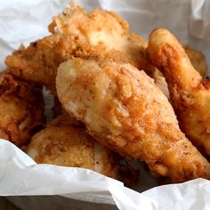 fried chicken sticks are in a basket with white paper on the side and one is slightly overcooked