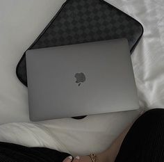 an apple laptop sitting on someone's lap in bed with their feet propped up