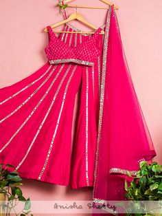 A three-piece Hot Pink Mirror Sharara set from the Anisha Shetty collection. This beautiful hot pink blouse in net fabric is paired with a dupion silk sharara pant. The hot pink color with sequence embroidery and mirror lace enhance this sharara set. The outfit is completed with a mirror lace net dupatta. Designer Pink Sharara With Dori Work, Pink Gota Work Sets For Navratri, Pink Sets With Gota Work For Navratri, Pink Chanderi Set For Reception, Pink Dori Work Sets For Eid, Diwali Pink Palazzo Set With Dori Work, Pink Chanderi Sharara For Reception, Party Wear Sharara With Gota Work For Eid, Festive Pink Sharara With Gota Work