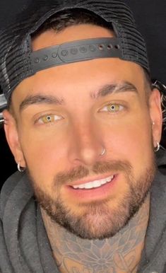 a close up of a person wearing a hat with tattoos on his face and neck