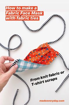 a hand holding an orange fabric mask with black and white stripes on it, next to the text how to make a fabric face mask with fabric ties from knit fabric or t - shirt scraps