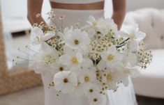 a bride holding a bouquet of white flowers