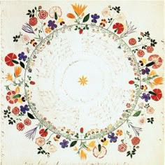 an embroidered cloth with flowers and leaves in the center, on a white ground mat